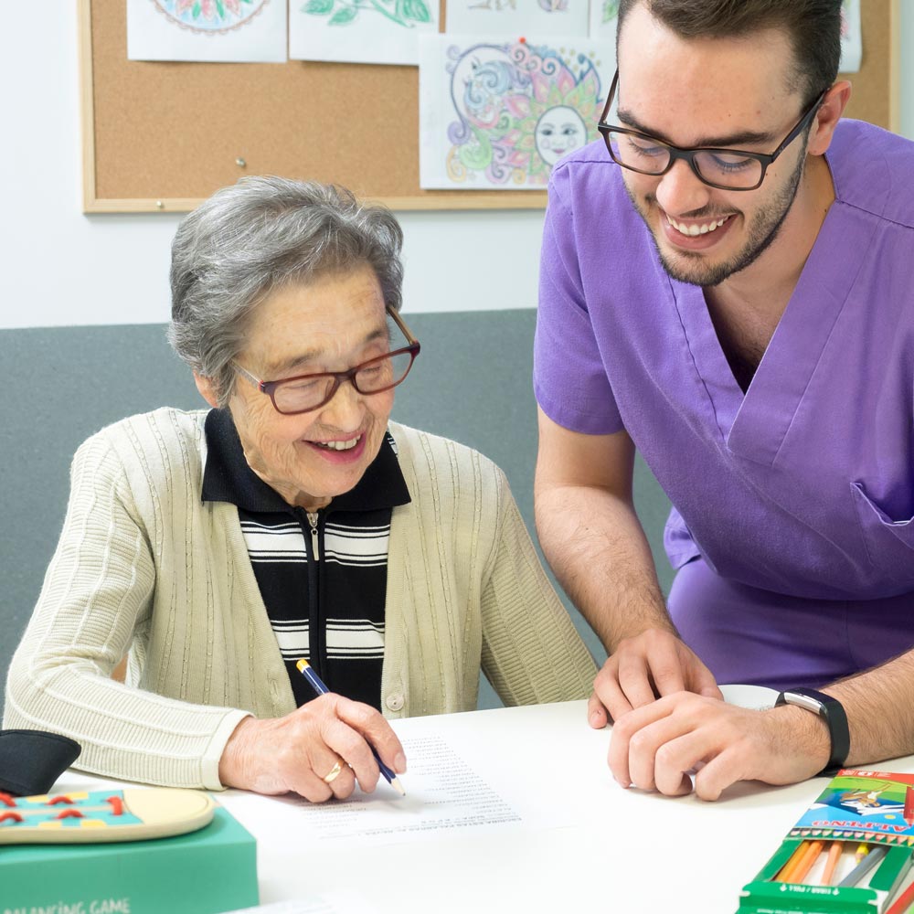 Un trabajador del centro de mayores ayuda a una de las residentes en un taller de creatividad